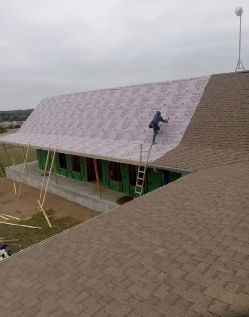 Worker preparing underlayment for a metal roof installation in Castle Rock